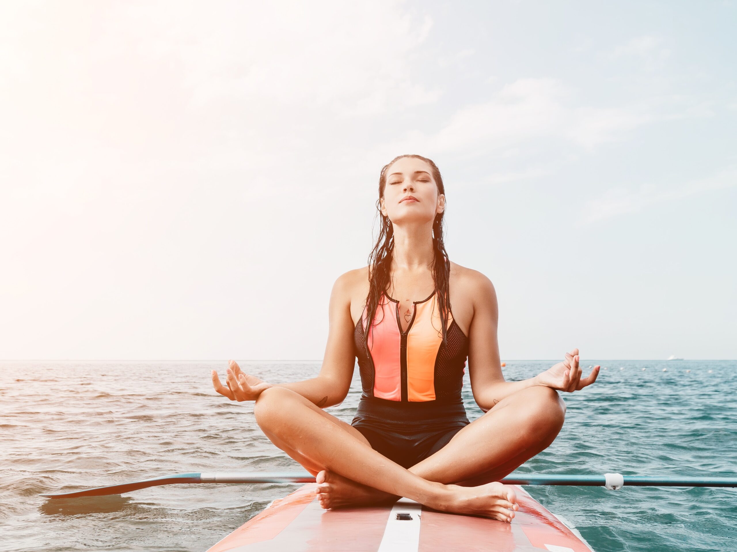 Mujer haciendo yoga sobre una tabla de paddle surfMujer haciendo yoga sobre una tabla de paddle surf Mujer haciendo yoga sobre una tabla de paddle surf